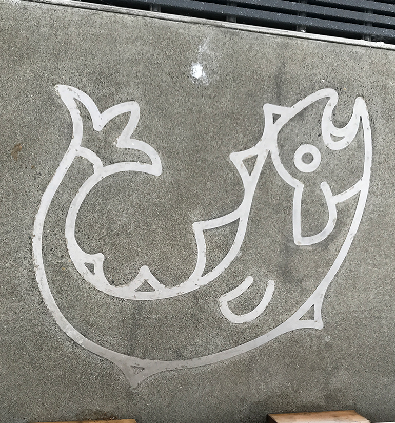 An image of a salmon made up of steel embedded into concrete. 