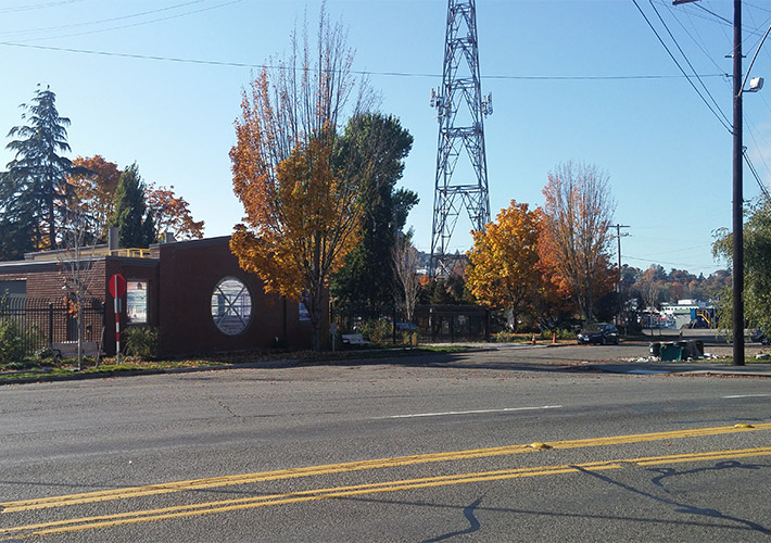 A red brick building beside a tree with orange leaves in the future site of Fremont vertical shaft at Leary Way Northwest and Northwest 36th Street.