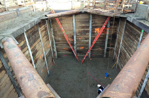 This photo shows crews excavating a large rectangular hole in the ground in Queen Anne. Steel bracings reinforce the corners of the rectangular hole.